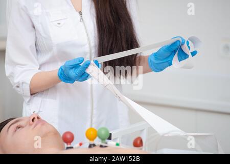 Cardiogram of the heart. Cardiologist is studying the testimony of an electrocardiograph. Cardiogram tape. Cardiology Stock Photo