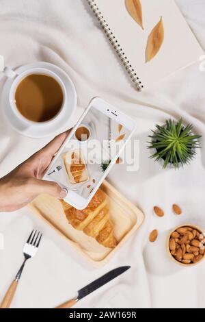 Coffee, croissant , plant, almond and notebook on a white desk was flat Stock Photo