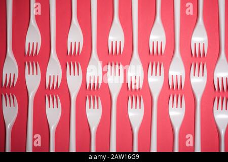 Disposable plastic cutlery on a pink table. Stock Photo