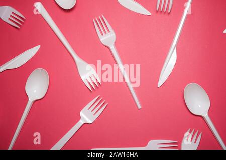 Disposable plastic cutlery on a pink table. Stock Photo
