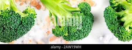 Broccoli florets close-up panoramic flat lay shot on a white background with pink Himalayan salt Stock Photo