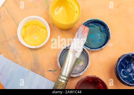 brush and jars of multi-colored paints with covers. Background for an article about drawing. Stock Photo