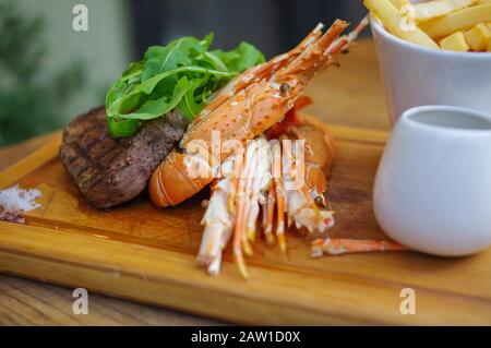 Surf and turf grilled lobster steak french fries on wood tray Stock Photo