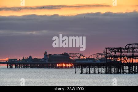 Brighton UK 6th February 2020 - The sun rises behind Brightons two piers on a cold bright morning . More fine settled weather is forecast for the next couple of days in Britain before stormy weather is set to arrive during the weekend  . Credit: Simon Dack / Alamy Live News