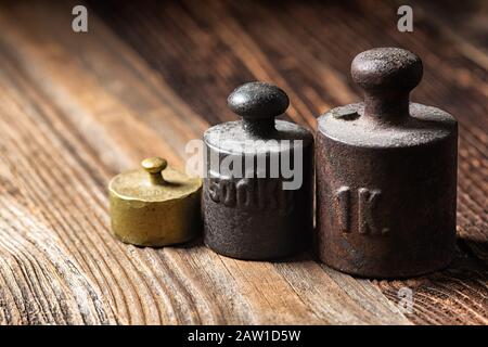 Old rustic metal weights on wooden table. Stock Photo