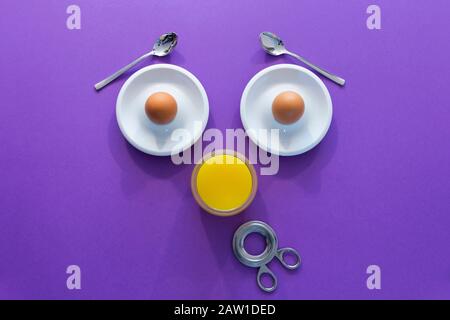 Fun breakfast concept with abstract astonished human face made of breakfast items on purple background Stock Photo