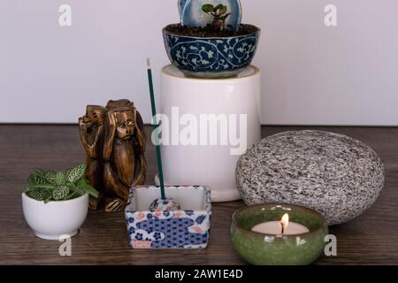 Home altar. Burning candle in a ceramic pot, incense sticks, stone and fresh plants. Spirituality at home concept. Daily meditation routine. Mini Zen Stock Photo