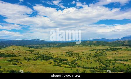 Tropical landscape: mountains with rainforest and hills with green grass.Mountains against the blue sky and clouds. Philippines, Luzon. Summer landscape.