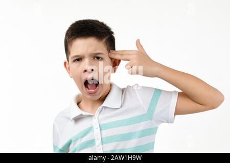 little boy in t-shirt shooting in temple with hand on white background. Stock Photo