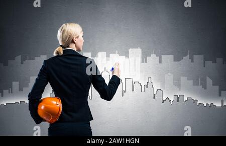 Businesswoman draws silhouette of business center Stock Photo