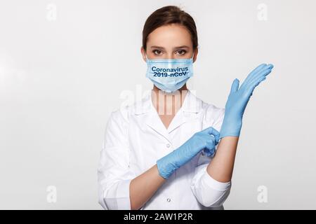 Young woman doctor in white uniform wearing mask and gloves. Coronavirus. 2019-nCoV. Stock Photo