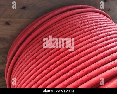 red coiled electrical cable on the wooden spool. Stock Photo