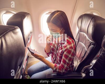 Asian tourist feeling sick, coughing ,wearing mask to prevent during travel time by airplane for protect from the new Coronavirus 2019 infection outbr Stock Photo