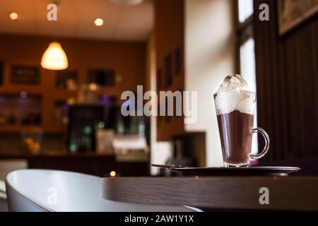 Coffee with whipped cream. Cinnamon and sugar. Waiting for friends in a coffee shop. Stock Photo