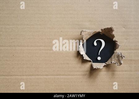 Torned corrugated box revealing question mark. Concept of mystery and uncertainty Stock Photo