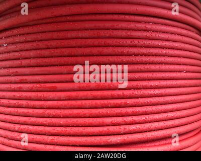 red coiled electrical cable on the wooden spool. Stock Photo
