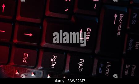 The computer keyboard, which is shot close to the abstract lights, is pressed at the enter. Hacking Concept. Stock Photo