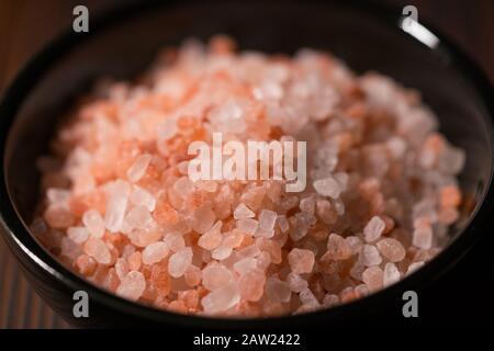 bowl of pink himalayan salt on dark wooden table Stock Photo