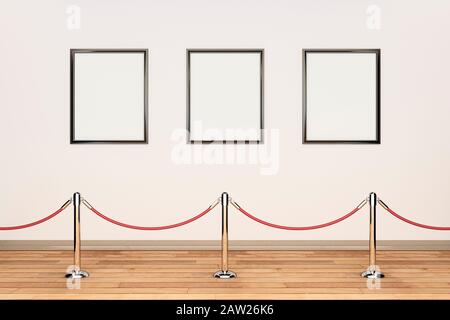 Three blank picture frames in a row on a cream wall in an art gallery with barrier rope and posts Stock Photo