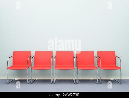 A row of five waiting room chairs in an empty room Stock Photo