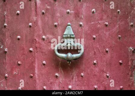antique medieval brass handle on an old entrance red door Stock Photo