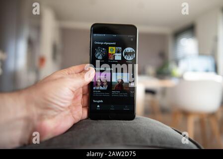 Amsterdam, The Netherlands, 02/06/2020, Man holding his phone, Spotify start screen on smartphone, mobile screen. Music content streaming subscription Stock Photo