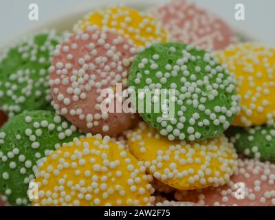 Pastel colored, green, yellow and pink white chocolate mint candies covered in white dot sprinkles piled up close. Stock Photo