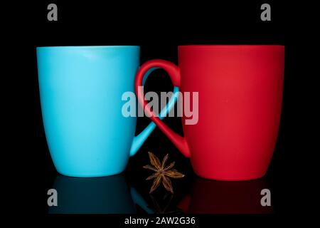 One whole aromatic brown badian with red ceramic cup and blue ceramic cup isolated on black glass Stock Photo