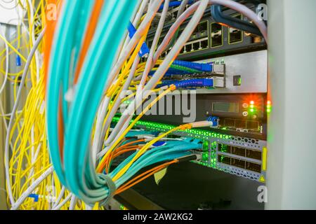 messy plex of wires in the server rack of the data center. High-speed Internet cables are connected to 10G interfaces of the central router Stock Photo