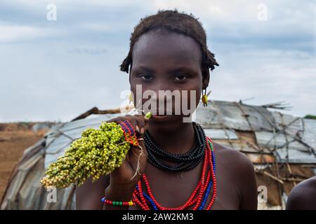 Omorate, Ethiopia - Nov 2018: Dasanech tribe woman chewing sorghum in front of the tribal house. Omo valley Stock Photo