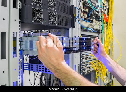Installation of a new server in a rack with computer equipment. Performing work to replace the server in the data center. The system administrator's h Stock Photo