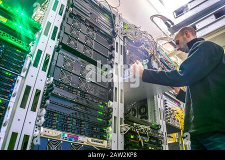 The engineer installs the new equipment in the server rack of the data center. The technical specialist works in the server room. Bottom view Stock Photo