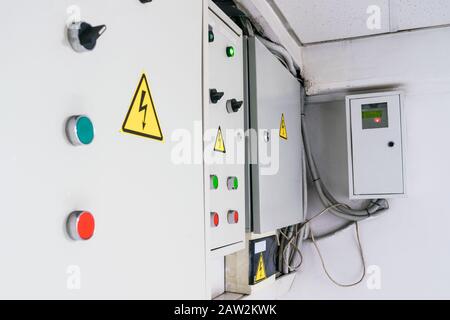 A few fuse boxes are installed on the wall in the basement. High voltage electrical control panel. Iron Electric Box Stock Photo