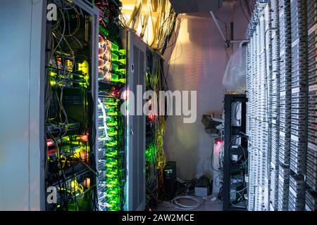 Many wires and computer equipment work in a dark server room. The server racks and the patch panel are in the data center Stock Photo