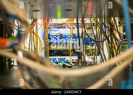 Many wires are in the rack with the switching equipment of the Internet provider. The communication cables and fiber optic patch cords are located in Stock Photo