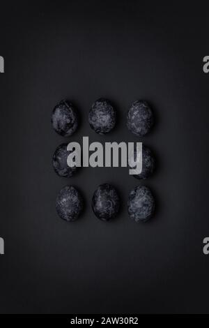 Handmade monochrome black textured painted eggs square pattern in the middle of composition on a black background. Happy Easter minimal concept Stock Photo