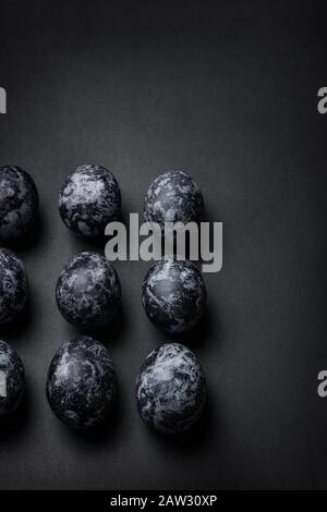 Handmade monochrome black textured painted eggs square pattern on a black background. Happy Easter minimal concept. Copy space, top view, vertical Stock Photo