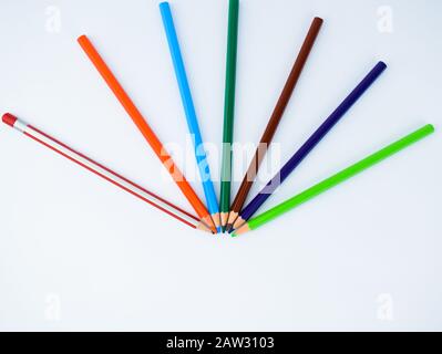 Top view of seven different colored pencils arranged in a half circle pattern on a white background Stock Photo