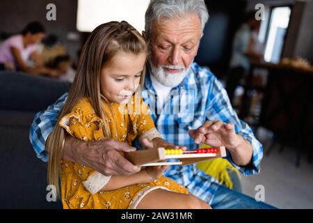 Grandfather and grandchild are smiling while playing with toys together at home Stock Photo
