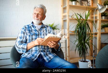 Senior man at home reading book and enjoying retirement, penison Stock Photo