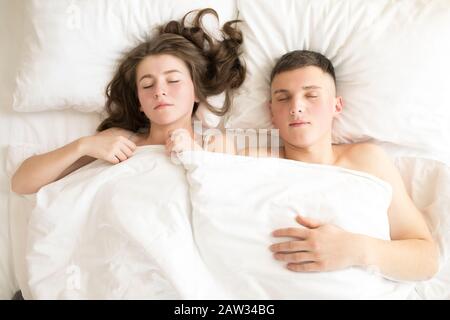 Top view of couple sleeping in bed under blanket. Stock Photo