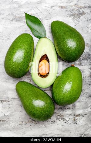 Fresh ripe organic green avocados and halve with leaf on gray concrete background, top view food concept. Minimal flat lay style avocados on gray Stock Photo