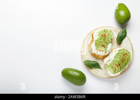 Two avocado toasts, avocados fruit, avocado sandwich. Fresh avocado sliced on toast of wheat bread, cream cheese. Avocado sprinkled with spices on a Stock Photo