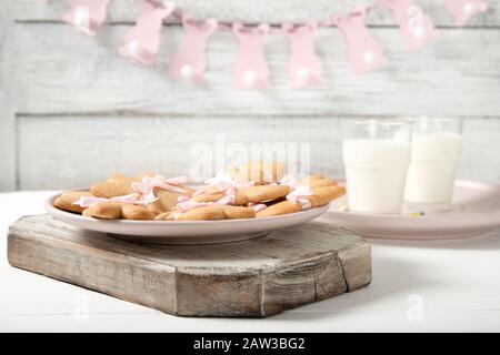 Easter cookies on a plate with a glass of milk on a wooden background. Easter bunnies. Easter garlands. Stock Photo