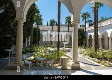 Italian courtyard in the Livadia Palace with palm trees and a fountain in the middle on a sunny day, Crimea. Stock Photo