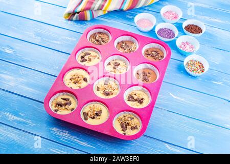 Pouring cake into silicone mold on blue wooden rustic background. Stock Photo