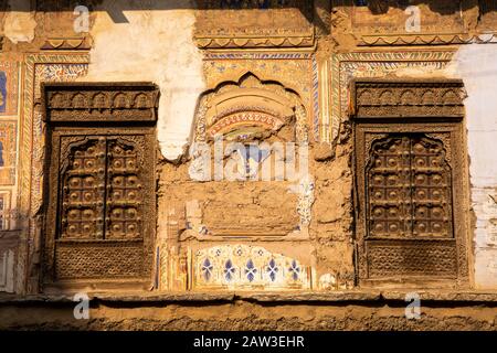 India, Rajasthan, Shekhawati, Mandawa, crumbling painted stucco between two wooden haveli windows Stock Photo
