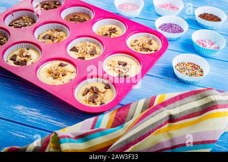 Pouring cake into silicone mold on blue wooden rustic background. Stock Photo