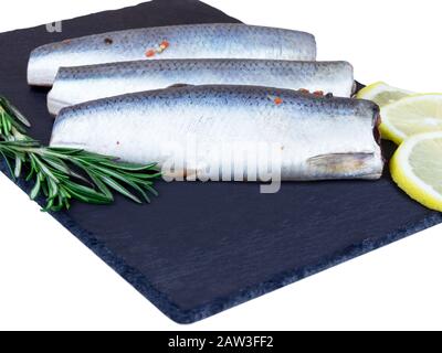 Salted herring with herbs and lemon on dark rustic background Stock Photo