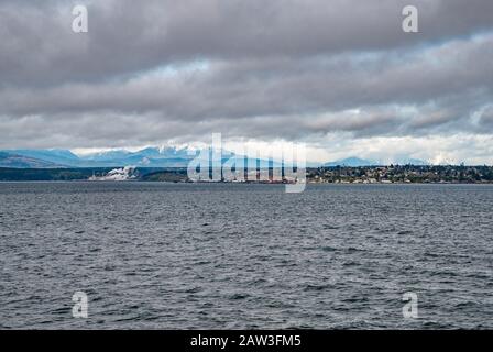 Port Townsend Paper Mill on left, Olympic Mountains in distance, view from ferry crossing Puget Sound Basin, Port Townsend, Washington, USA Stock Photo